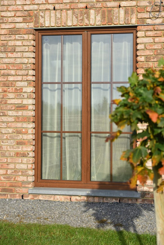 Porte-fenêtre PVC teinte bois sur une façade en brique, PIERRET